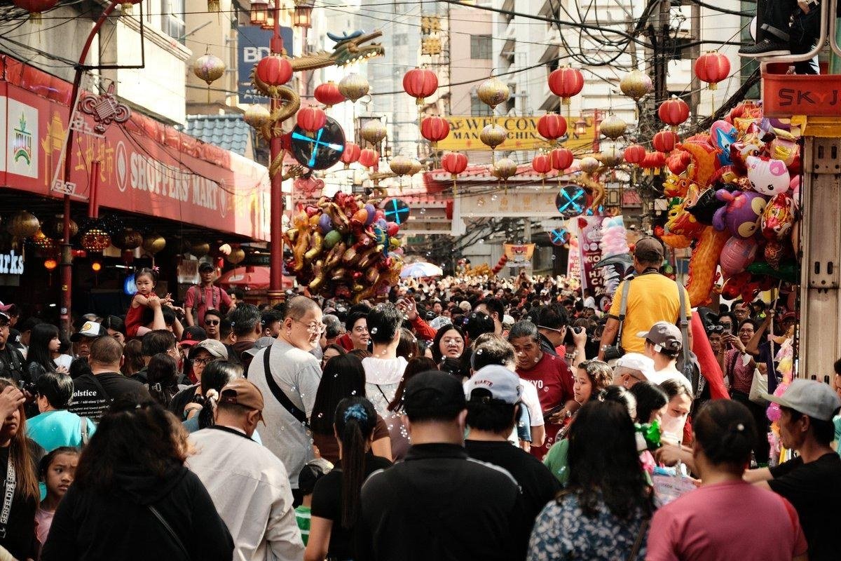 Busy Ongpin Street in Manila's Chinatown, decorated with red lanterns and golden dragons above pedestrians and market stalls