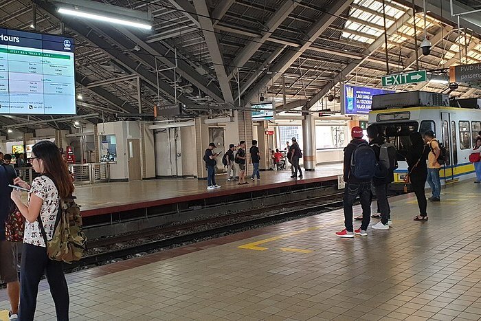 Passengers waiting beside the tracks at Doroteo Jose LRT station in Manila, with a train stopped at the platform