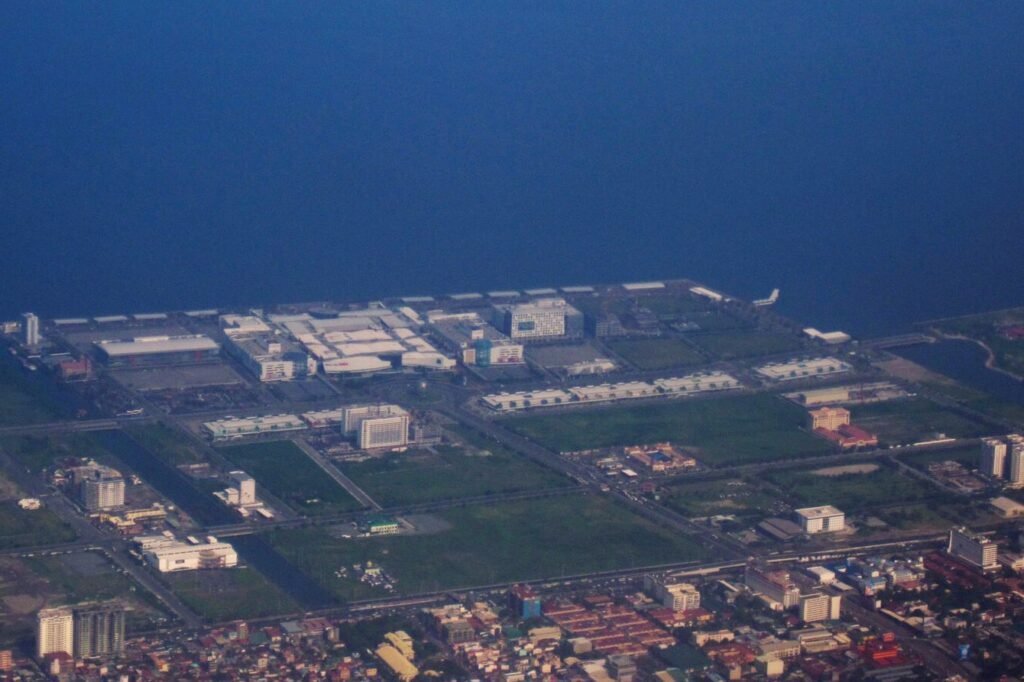 Aerial view of the SM Mall of Asia complex beside Manila Bay, showing shopping buildings, roads and the waterfront