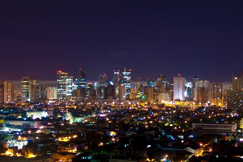 Makati skyline at night with illuminated high-rise buildings and city lights across Metro Manila