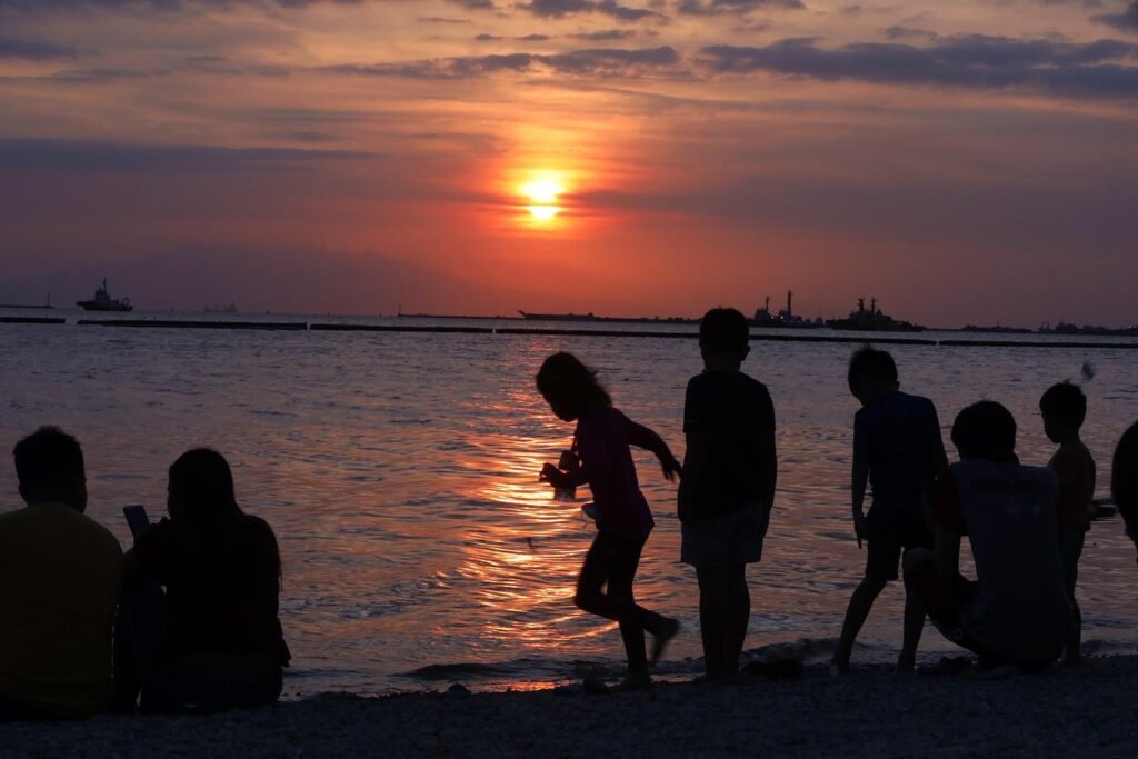 Visitors silhouetted against a brilliant golden sunset over Manila Bay