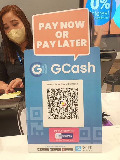 GCash QR code payment sign at a store checkout in the Philippines, with a cashier behind the counter