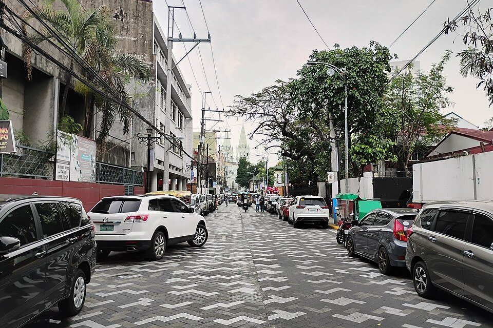 Hidalgo Street in Quiapo, Manila, with parked vehicles, patterned pavement and buildings lining the road