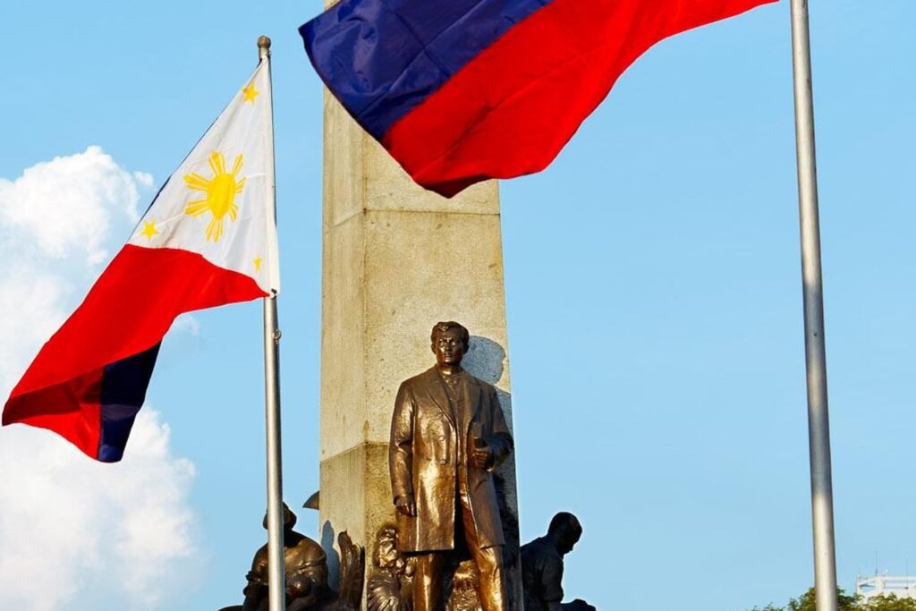 Close-up of the Rizal Monument in Manila, with the statue of José Rizal and Philippine flags flying on either side