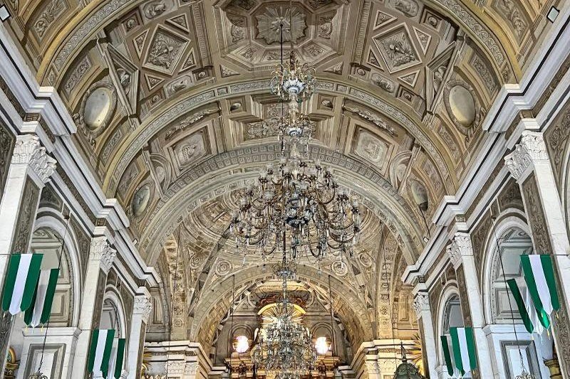Ornate vaulted ceiling of San Agustin Church in Manila, with decorative paintings, arches and hanging chandeliers