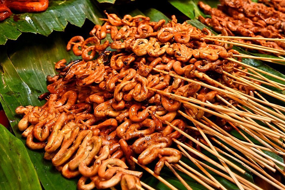 Grilled Filipino isaw, skewered chicken intestines, displayed on green banana leaves