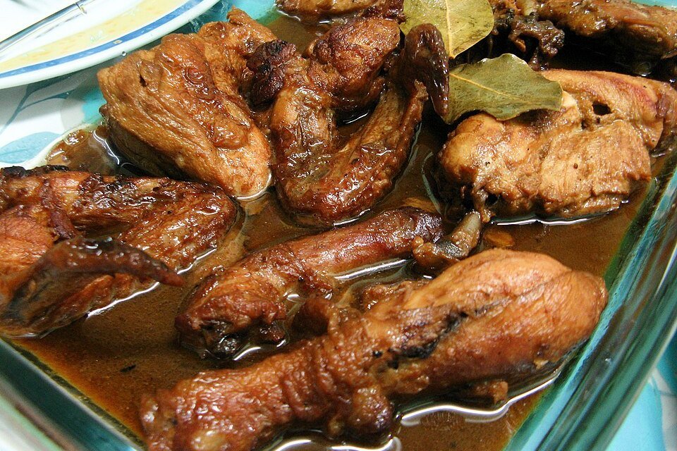 Filipino chicken adobo with browned chicken pieces simmered in a dark sauce with bay leaves