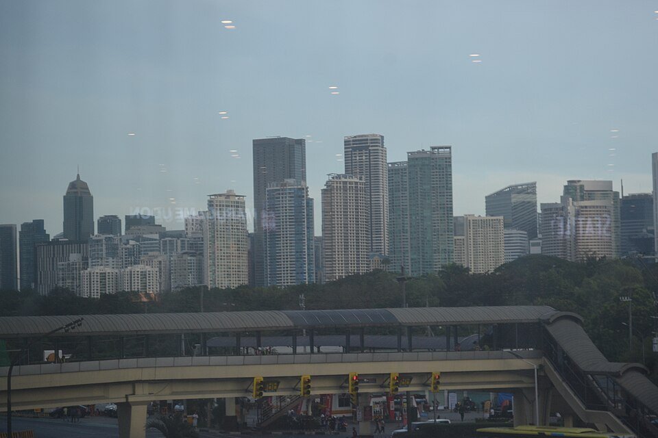 Daytime skyline of Bonifacio Global City with modern high-rise buildings and a pedestrian overpass in the foreground